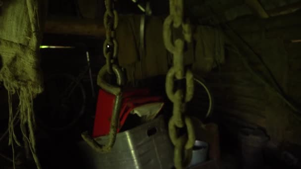 Ржавые цепи свисают с потолка и болтаются в заброшенном подвале, металлическая цепь и крючок двигаются в старом амбаре — стоковое видео