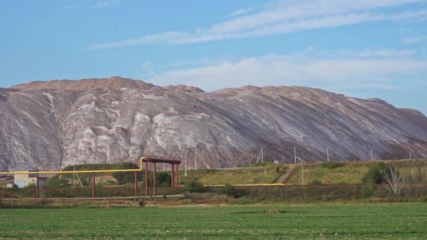 Gli uccelli sorvolano i cumuli di cloruro di potassio e il gasdotto. Estrazione di fertilizzanti a base di sale e potassio in una cava e lavorazione di minerali, terriconi e cumuli di rifiuti di potassio. Industria mineraria — Video Stock