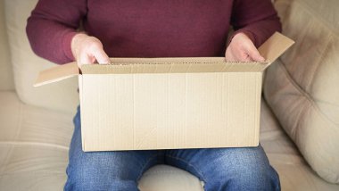 Bir adam karton bir kutudan bir paket açıyor.