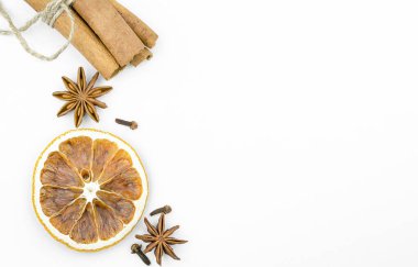 Beyaz arka planda kurutulmuş portakal, tarçın, anason ve karanfil.