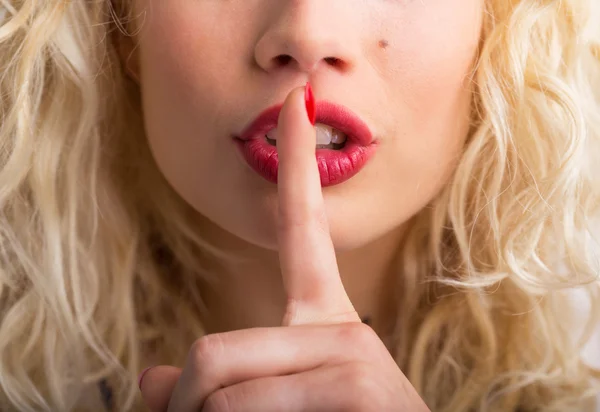 Vrouw met haar vinger tegen haar lippen gedrukt — Stockfoto