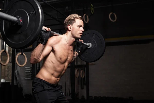 Hombre en forma haciendo escuadrones con pesas en sus hombros — Foto de Stock