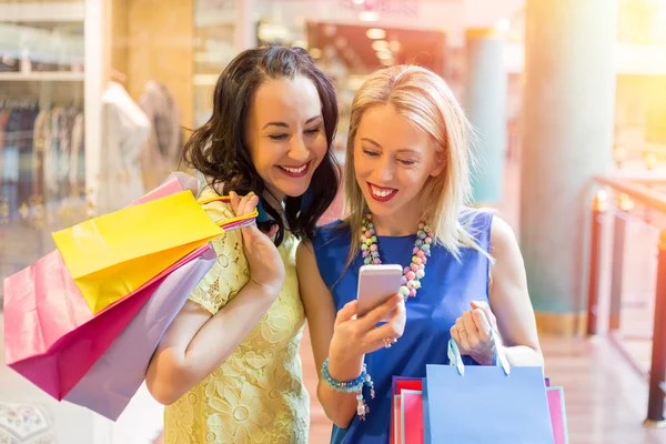 Дві жінки дивляться на смартфон під час покупок — стокове фото