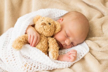 Oyuncak ayı ile birlikte uyuyan bebek