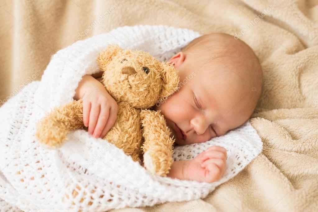 Infant sleeping together with teddy bear