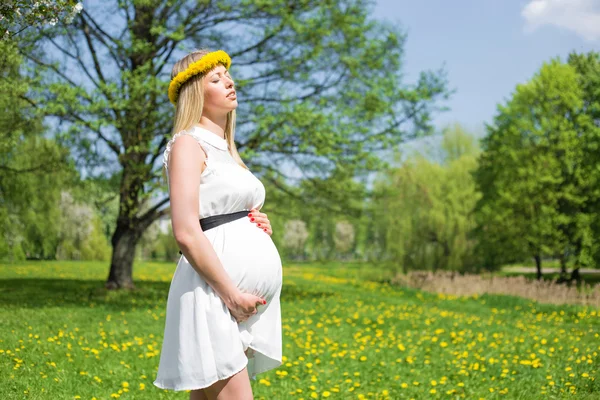 Pregnant woman in white dress holding her belly — Stock Photo, Image