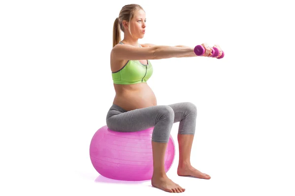 Pregnant woman working out on medicine ball with dumbells in her hands — Stock Photo, Image