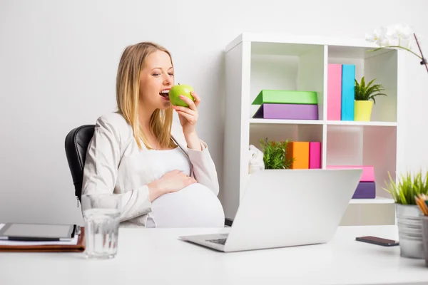 Schwangere isst während der Arbeit am Laptop Apfel — Stockfoto