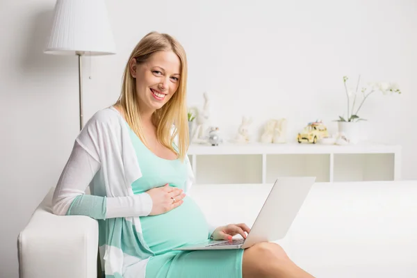 Glad och gravid kvinna som arbetar på dator — Stockfoto