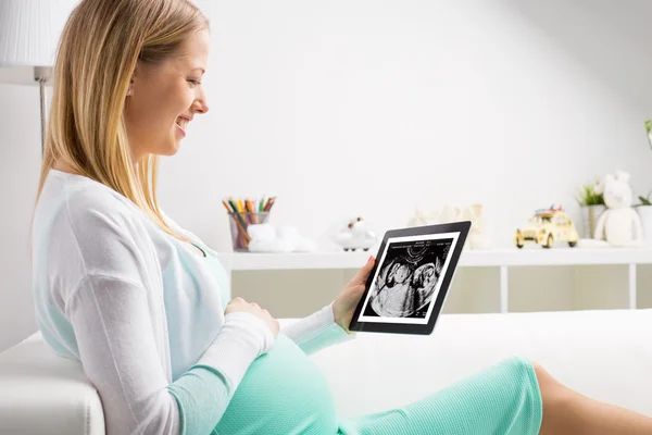Hamile kadın ultrason sonuçlarına bakmak için tablet kullanma — Stok fotoğraf