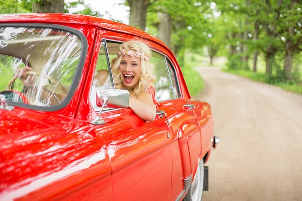 Mulher engraçada se divertindo dirigindo carro vintage vermelho — Fotografia de Stock