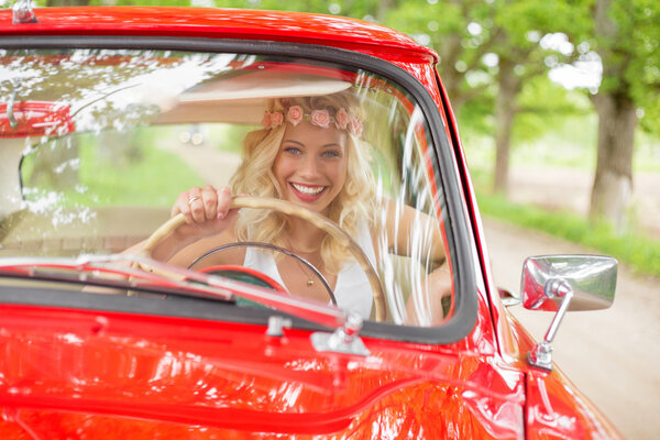 Woman sitting in retro car and smiling