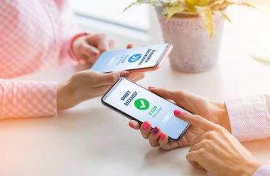 Kadın arkadaşına cep telefonu kullanarak para gönderiyor.
