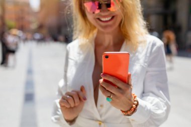 Dışarıda elinde cep telefonu olan bir kadın. Telefona odaklan..