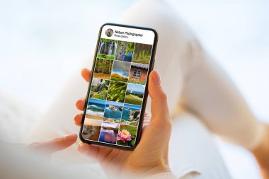 Cep telefonundaki doğa ve manzara fotoğraflarına bakan kişi