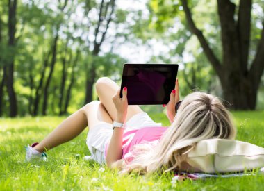 Tablet bilgisayar açık havada kullanan rahat genç kadın