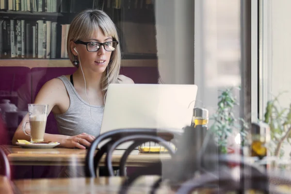 Ung kvinde arbejder med computer i cafe - Stock-foto