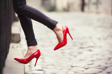 Eski şehirde siyah deri pantolon ve kırmızı yüksek topuk ayakkabı giyen kadın