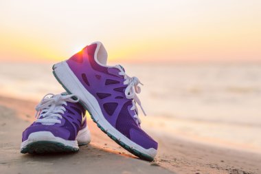 Pair of running shoes on the beach at sunset