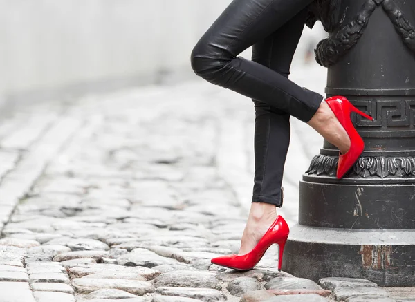 Γυναίκα, φορώντας μαύρο δερμάτινο παντελόνι και τα κόκκινα ψηλοτάκουνα παπούτσια στην παλιά πόλη — Φωτογραφία Αρχείου