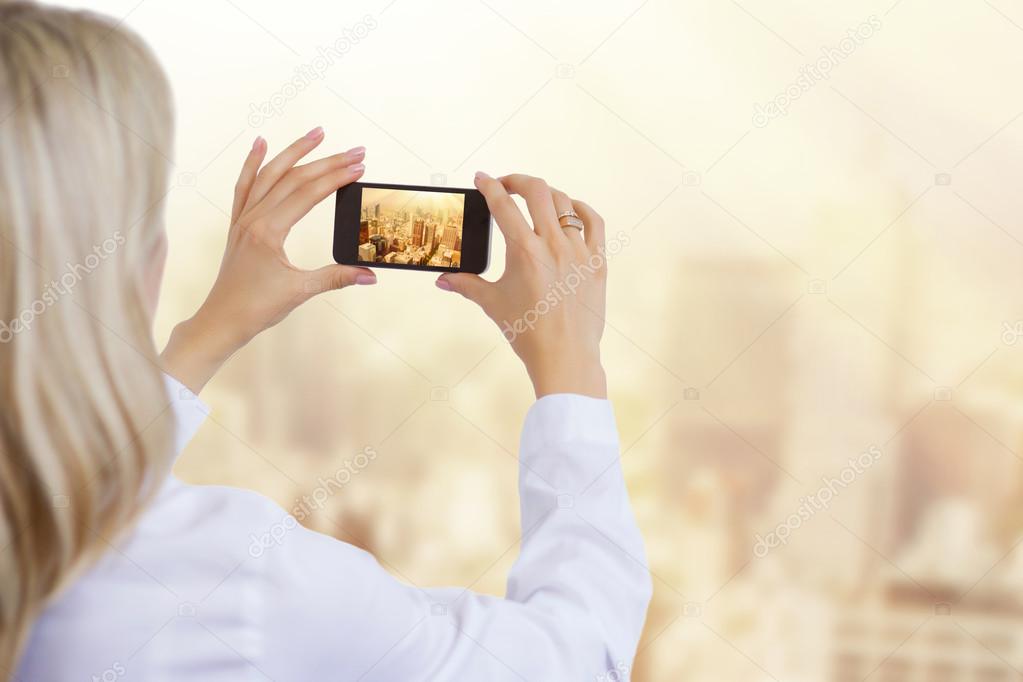 Woman taking photo of city in morning light, business and successful corporate career concept