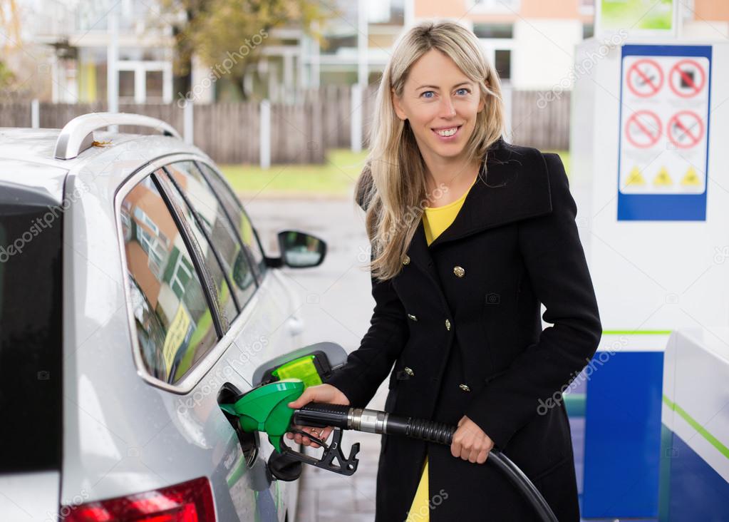 Young woman refilling car in gas station