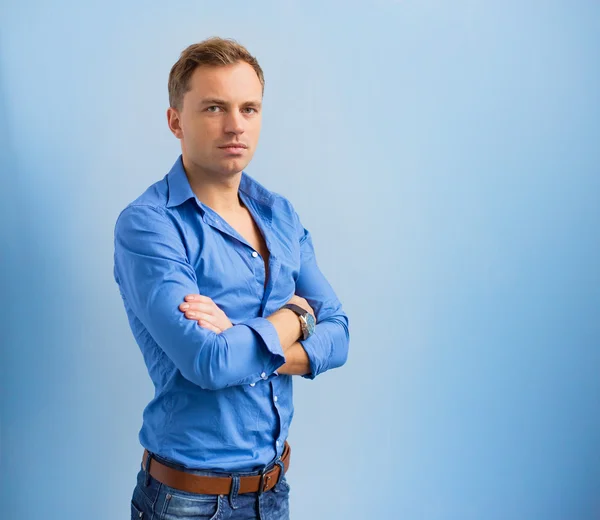 Retrato de hombre guapo inteligente con los brazos cruzados sobre fondo azul —  Fotos de Stock