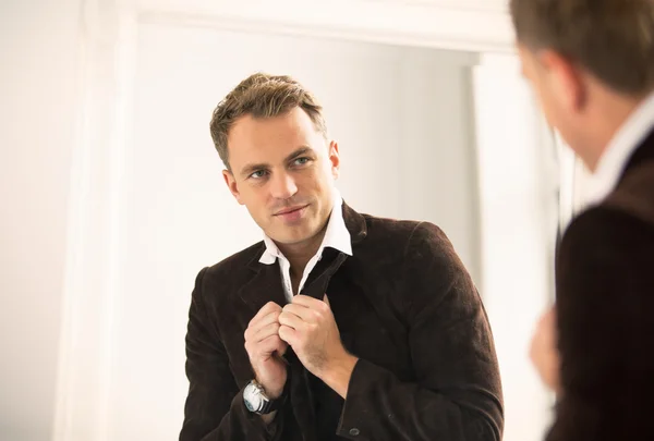 Hombre guapo mirándose en el espejo — Foto de Stock