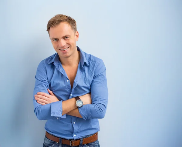 Portrait of smart and confident handsome man standing against blue background Stock Photo