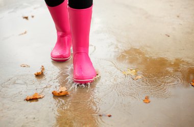 Kadın pembe kauçuk ile su birikintisi sonbaharda yürüme bot