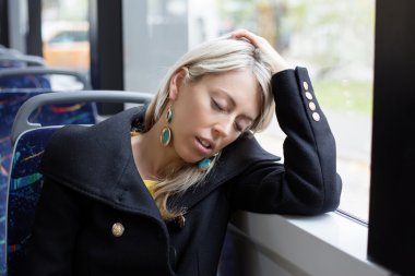 Tired woman sleeping while riding to work in public transport clipart