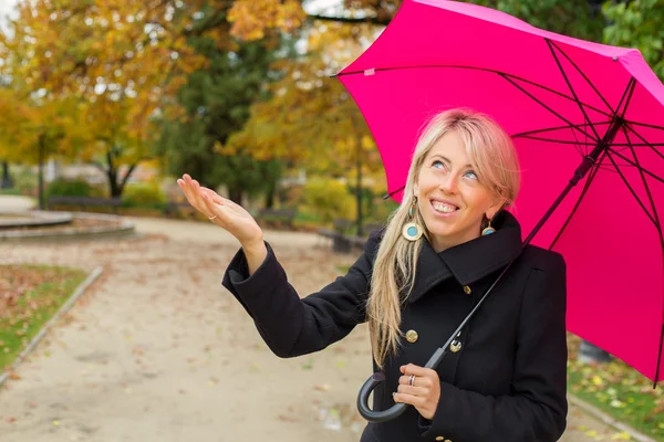 Mujer con paraguas rosa disfrutando del clima otoñal lluvioso — Foto de Stock