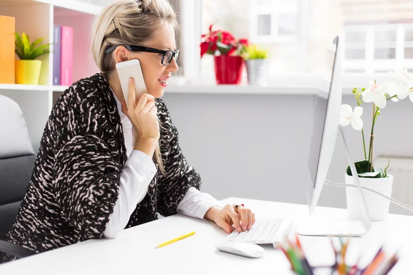 Woman talking on phone while working with computer — Stock Photo, Image