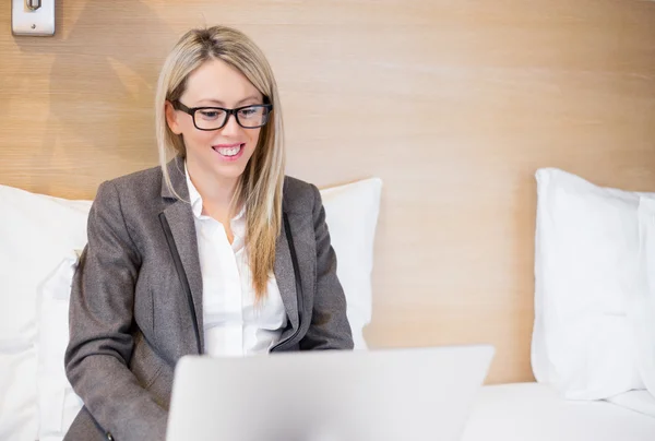Business woman working with laptop computer in bed — Stock Photo, Image