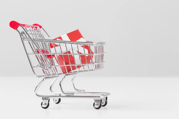 Small present box in miniature shopping cart model — Stock Photo, Image