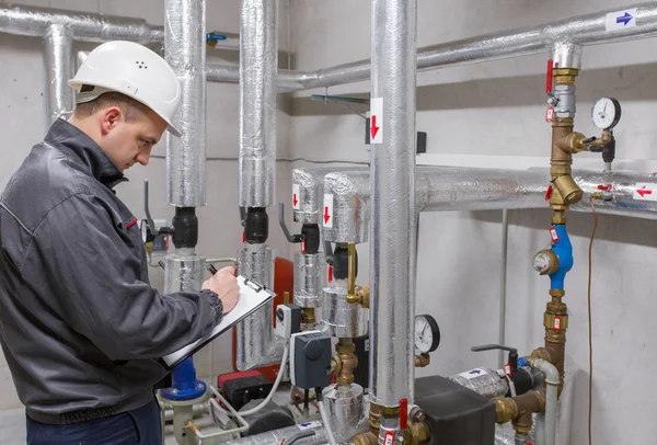 Técnico inspeccionando el sistema de calefacción en la sala de calderas —  Fotos de Stock