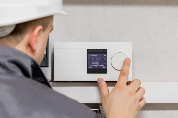 Engenheiro ajustando o termostato para um sistema de aquecimento automatizado eficiente — Fotografia de Stock