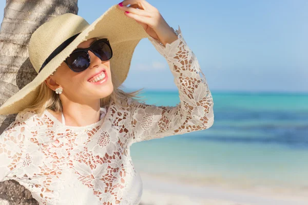 Mulher alegre com chapéu de verão em pé sob palmeira na praia tropical — Fotografia de Stock