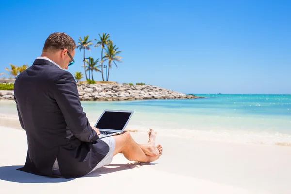 Бизнесмен использует ноутбук на тропическом пляже — стоковое фото