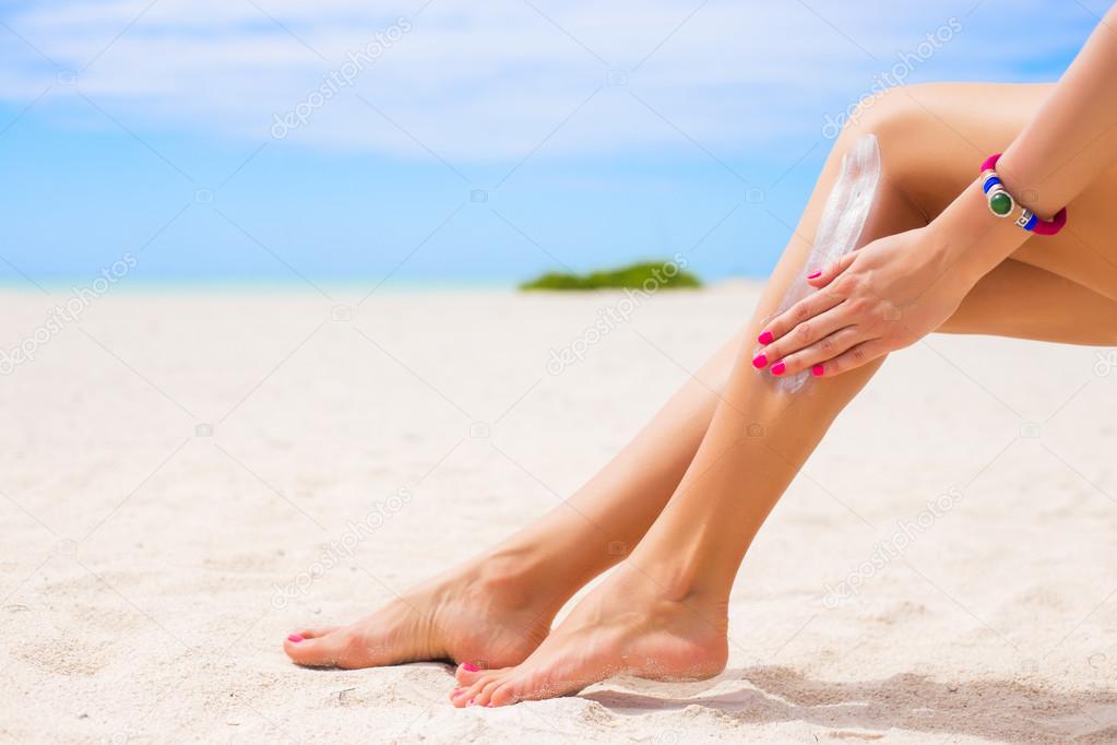 Woman applying sunscreen on her legs