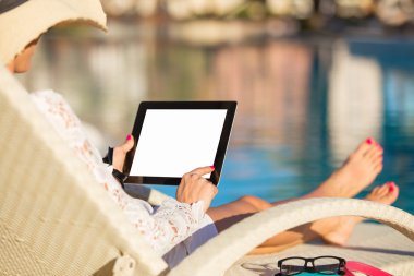 Havuz kenarında tablet bilgisayar kullanan kadın