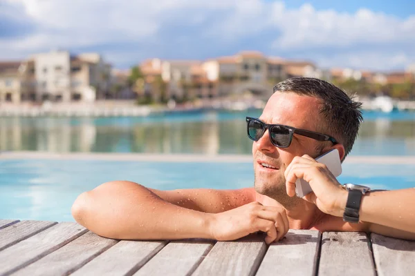 Hombre hablando por teléfono mientras se relaja en la piscina — Foto de Stock