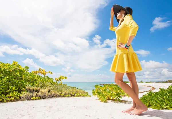 Modna kobieta lato czarny kapelusz i żółtej sukience na plaży — Zdjęcie stockowe