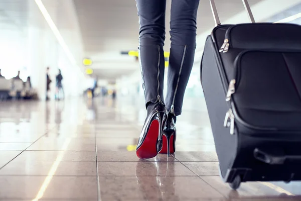 Woman walking through airport with luggage Stock Photo