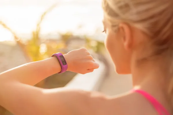 Woman looking at wearable fitness device — Stockfoto