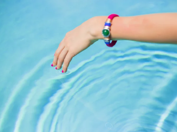 Woman touching swimming pool's water surface with fingers — Zdjęcie stockowe