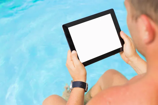 Homem segurando tablet computador junto à piscina — Fotografia de Stock