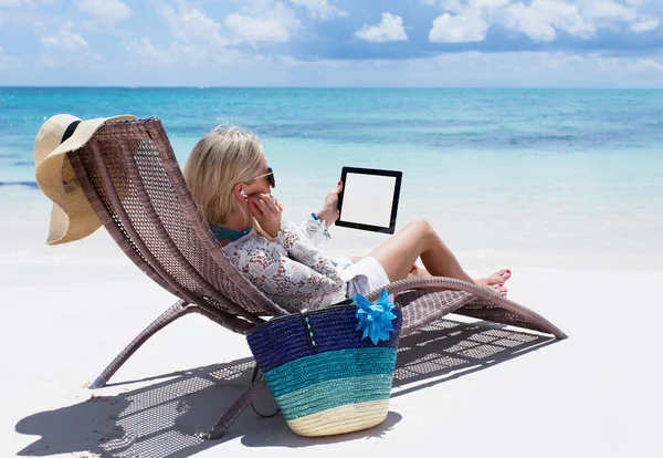 Donna che si rilassa sulla spiaggia e ascolta musica sul suo computer tablet digitale — Foto Stock