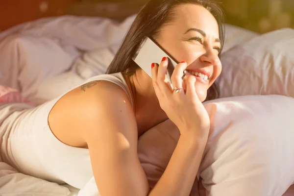 Mujer hablando por teléfono en la cama —  Fotos de Stock