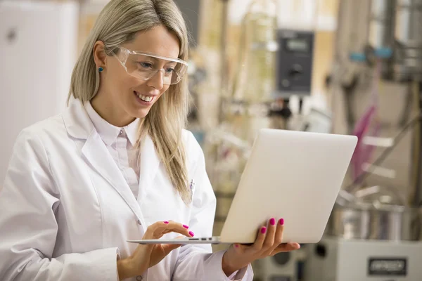 Química feminina trabalhando com computador portátil no laboratório — Fotografia de Stock